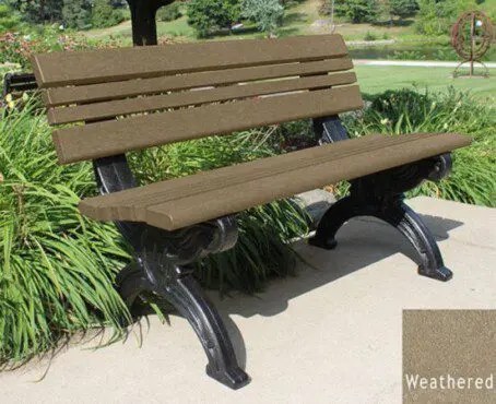 The Cambridge 4 ft recycled plastic park bench is very stylish with the ornately molded black frames that look like cast metal but are made of recycled plastic. The weathered wood color seat and back are made of 2"x 2" slats set between 2" x 4" bullnose edge boards. It's placed on a concrete pad in a park next to a flower bed.