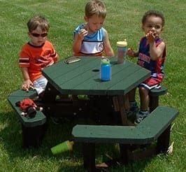 An Open Hexagon outdoor youth picnic table. This is the kid size version of our Open Hex Table and perfect for ages 3-6. Made out of 100% recycled HDPE plastic. Shown with a brown frame and green top and seat boards.